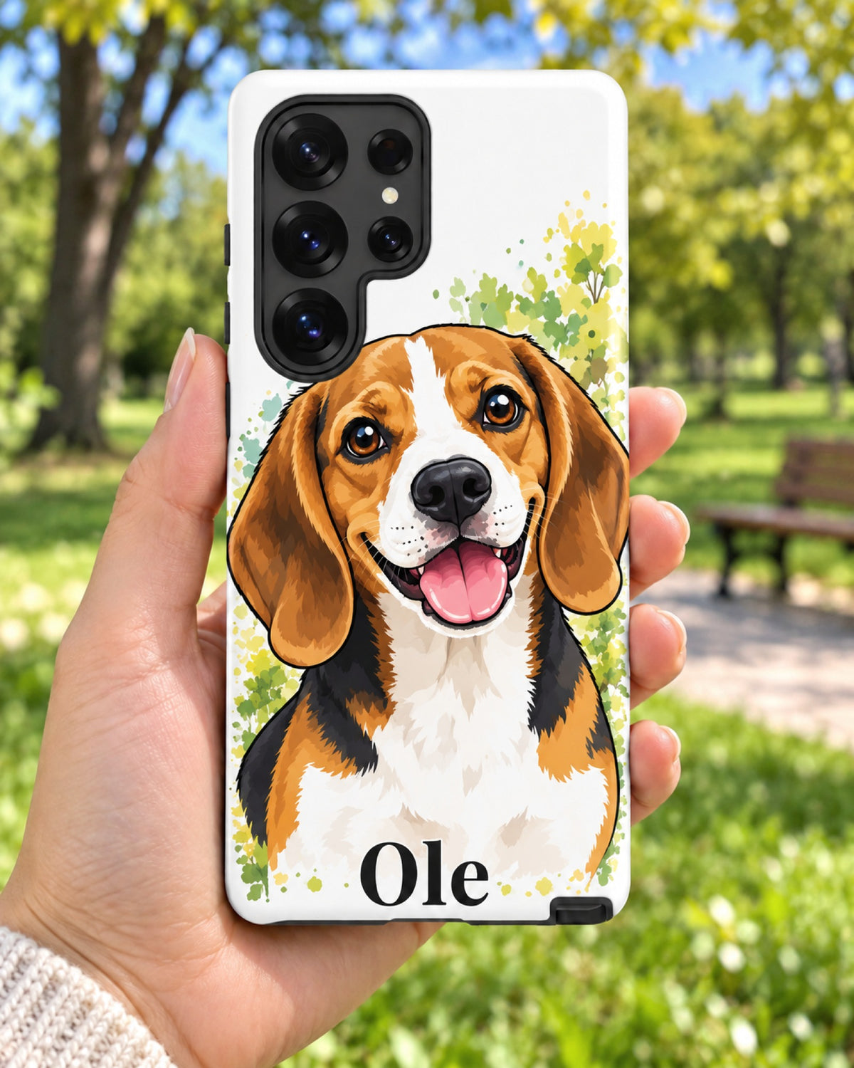 Samsung-Hülle mit Beagle im Cartoon-Stil und Namen Ole, eine Hand hält das Handy im sonnigen Park