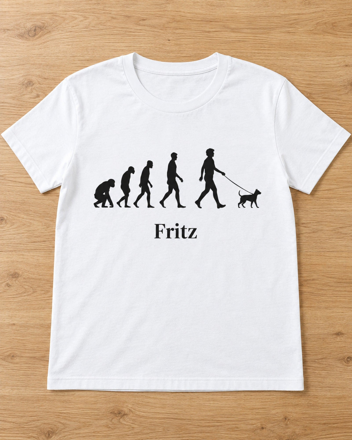 Weißes T-Shirt Pet Evolution mit Silhouetten vom Affen zum Menschen mit Hund und Namen Fritz, flach auf Holzboden gelegt