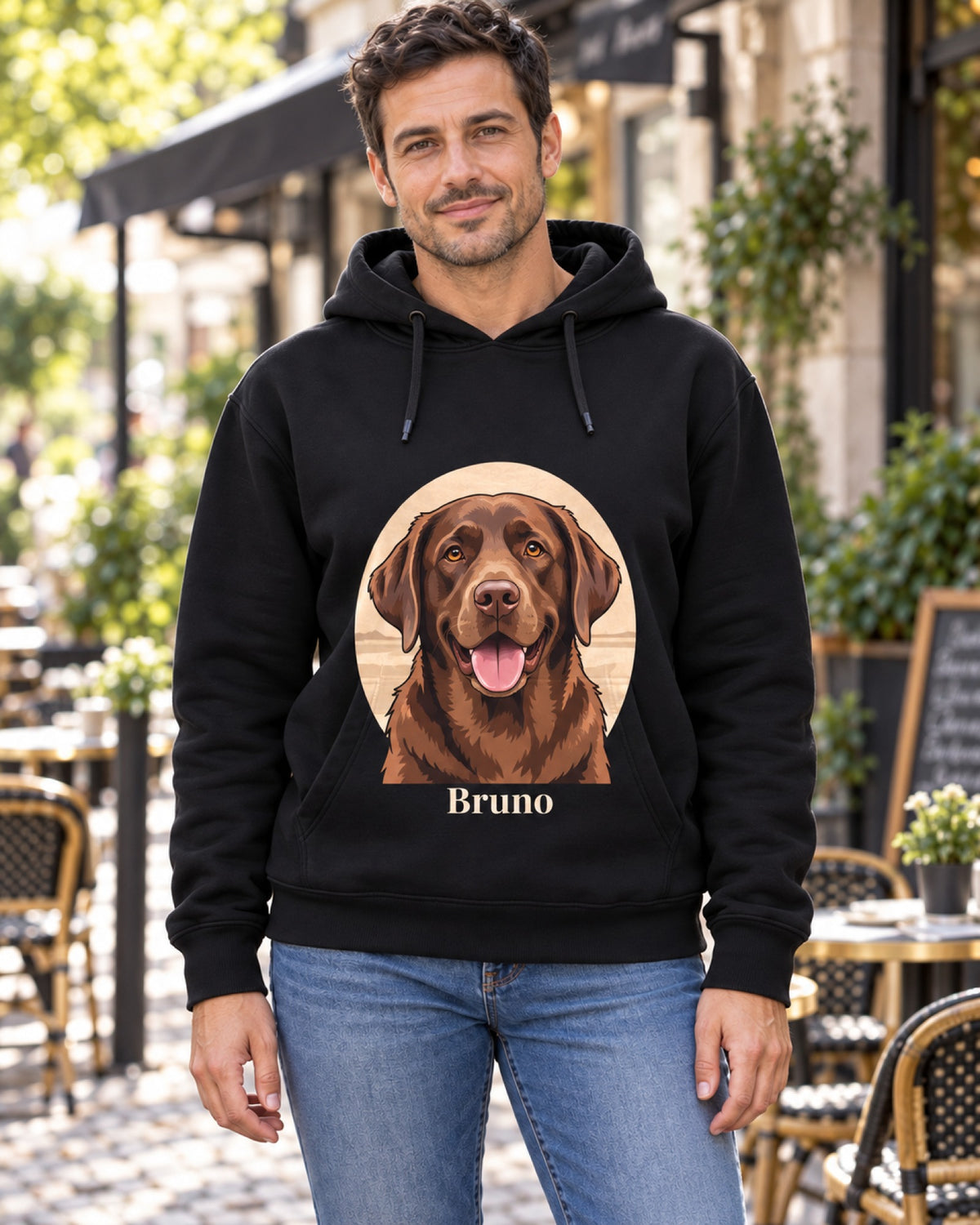 Mann vor einem Café im schwarzen Hoodie mit braunem Labrador Bruno im Cartoon-Stil auf der Brust