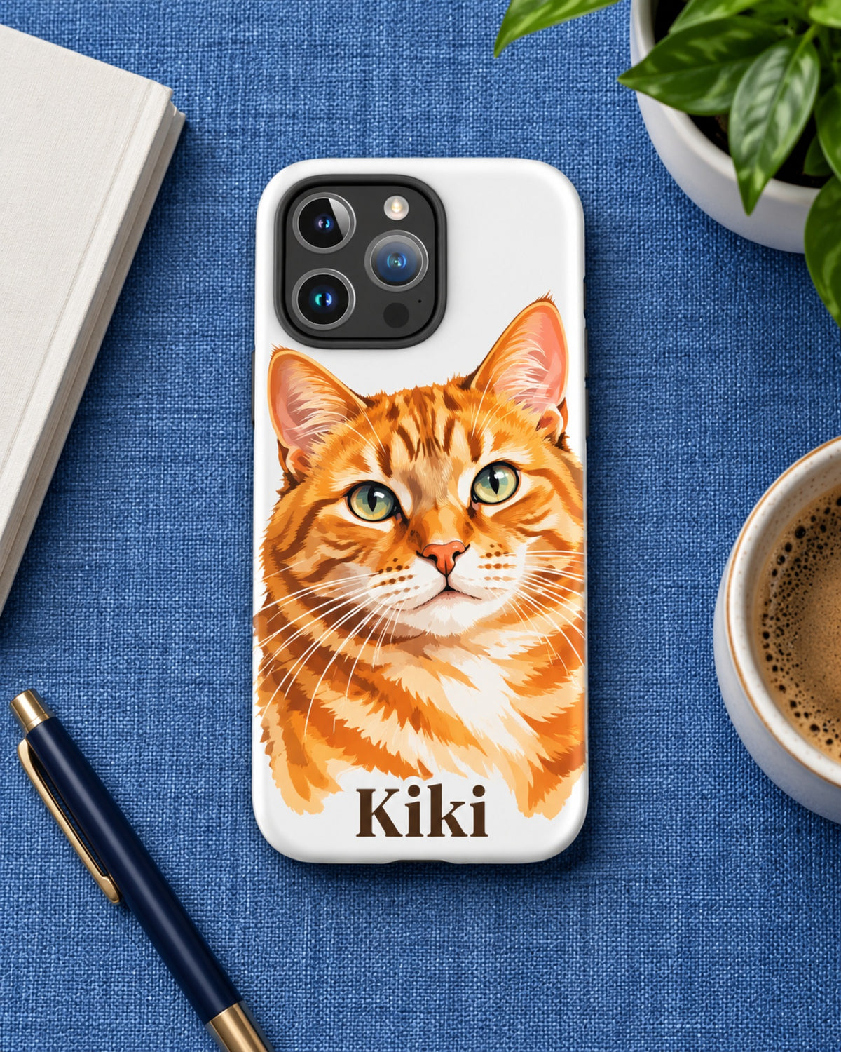 iPhone-Hülle mit roter Tigerkatze im Aquarell-Stil und Namen Kiki, das Handy liegt auf einer blauen Leinendecke