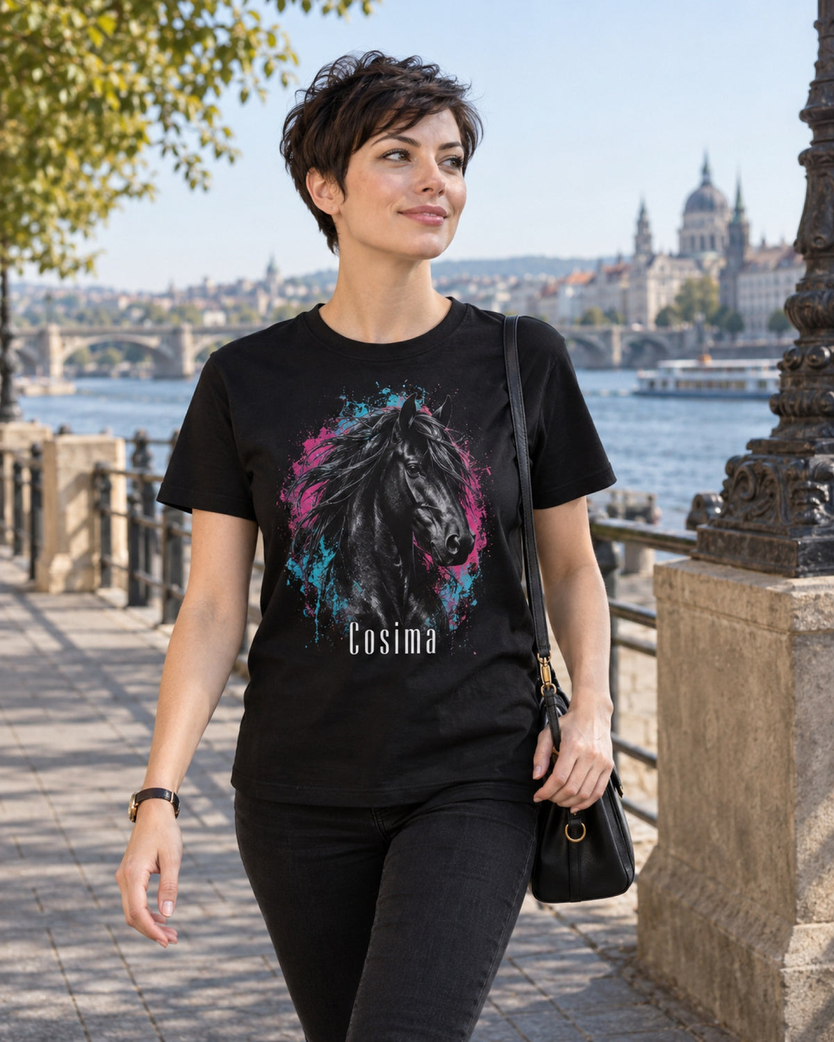 Frau im schwarzen T-Shirt mit Rappen-Portrait im Street-Art-Stil und Namen Cosima am Fluss