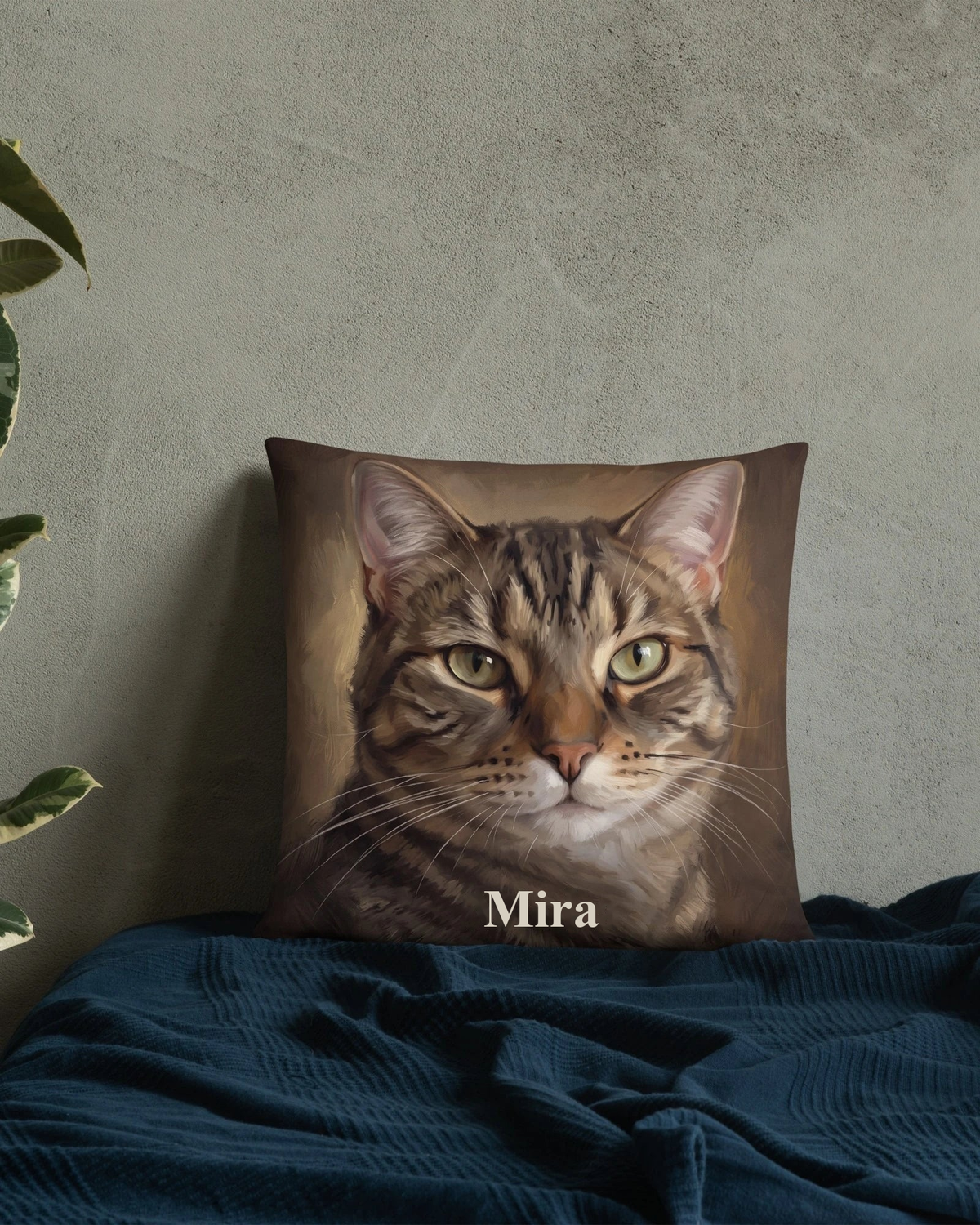 Kissen mit Katzenportrait im Ölgemälde-Stil und Namen Mira vor einer Wand