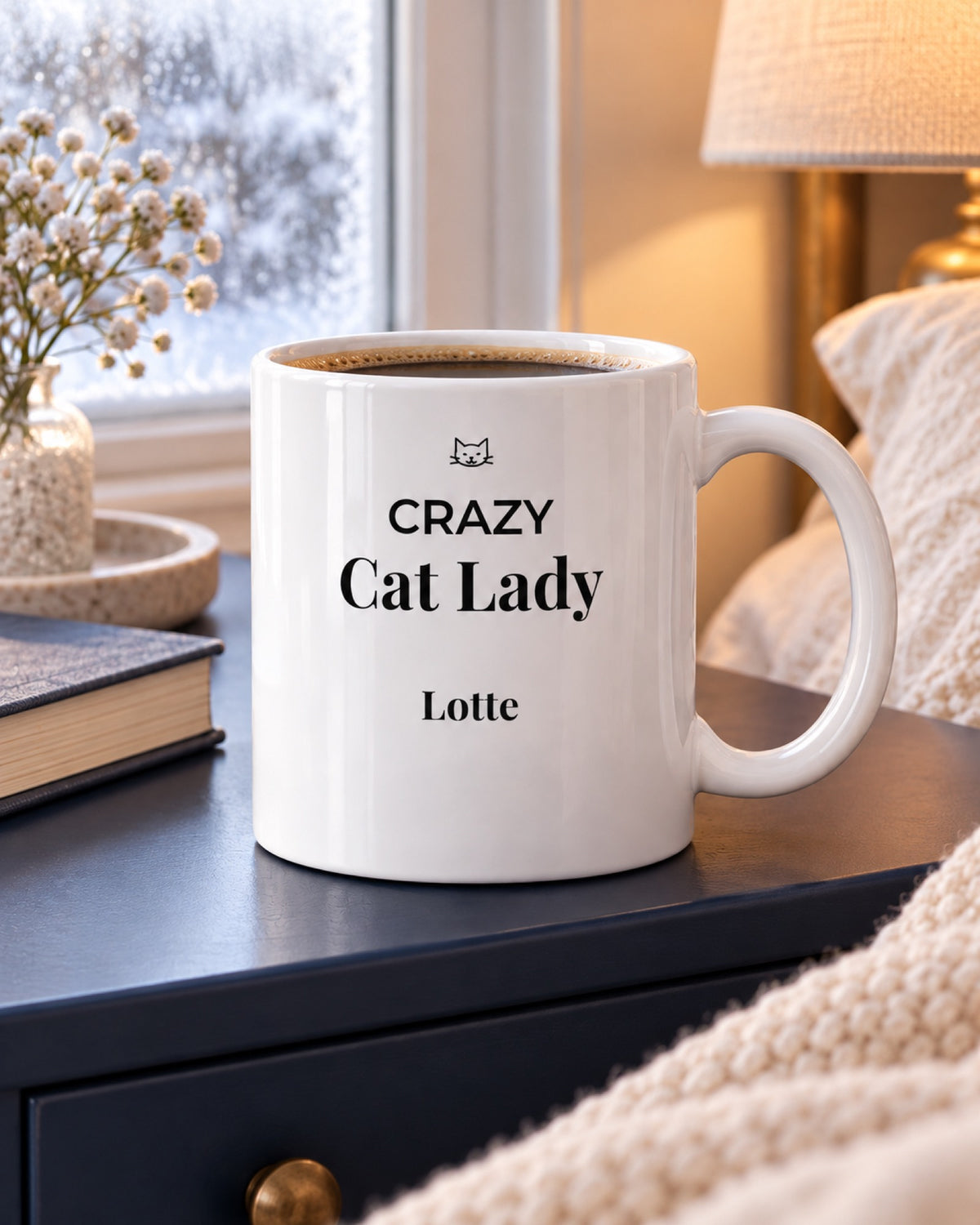 Weiße Keramiktasse Crazy Cat Lady Tasse mit Namen deiner Katze auf einem dunkelblauen Nachttisch im Wintermorgen mit Beispielname Lotte