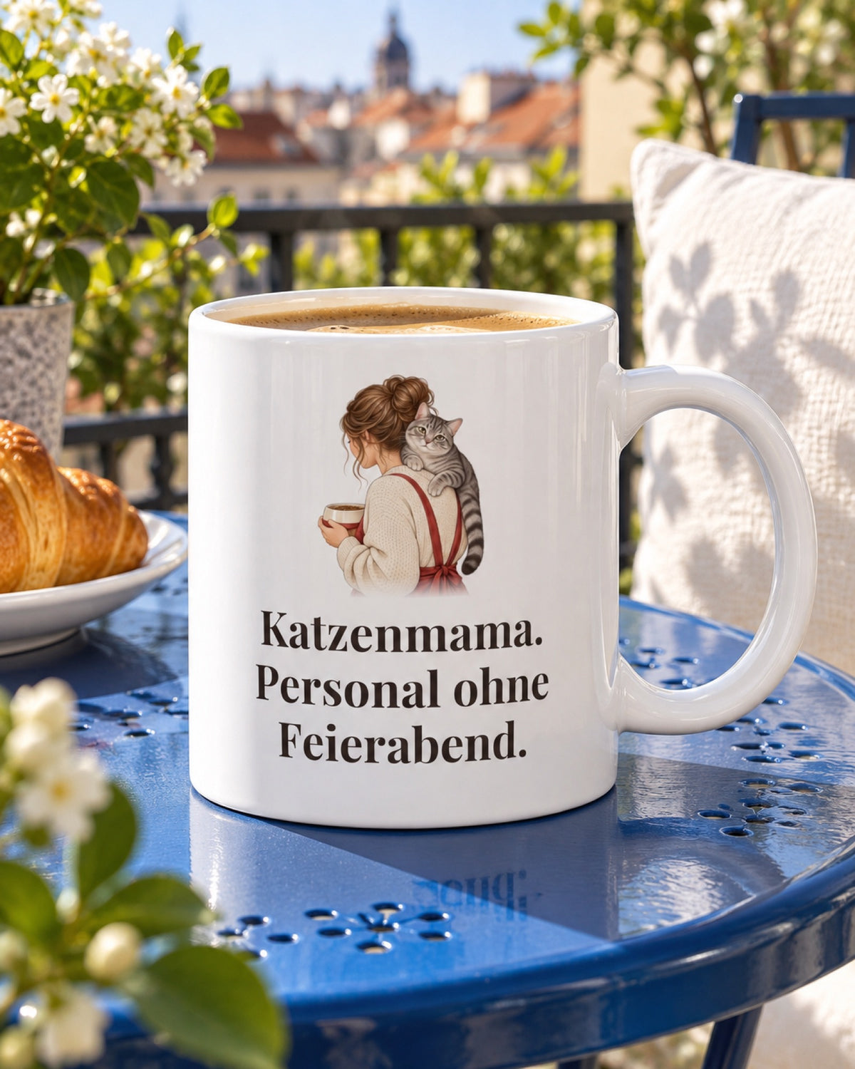 Weiße Keramiktasse Katzentasse mit Spruch: Katzenmama. Personal ohne Feierabend. auf einem blauen Balkontisch