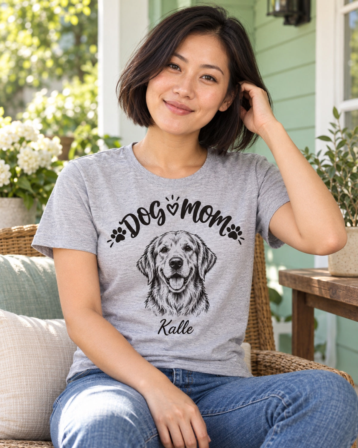 Frau im graumelierten Dog Mom T-Shirt mit Golden Retriever Kalle als monochromer Linienzeichnung auf einer mintgrünen Veranda