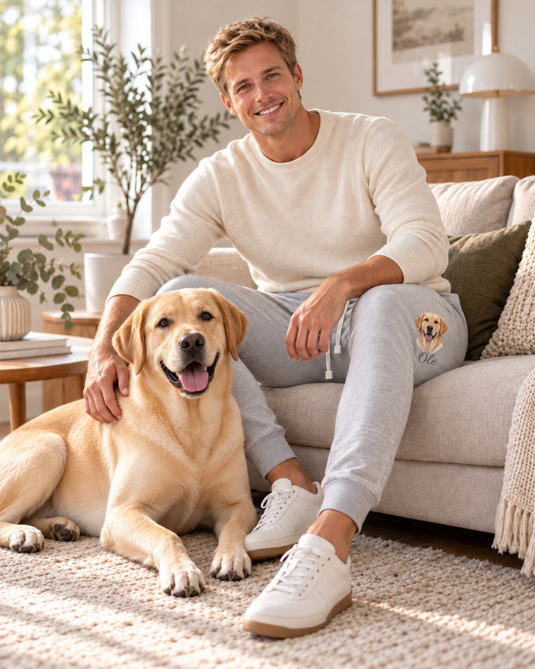 Personalisierte Jogginghose hellgrau mit Tierportrait, Herrenmodell getragen auf dem Sofa, Hund Ole