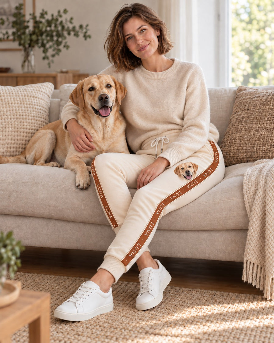 Personalisierte Jogginghose Signature Stripe mit Hundename im Seitenstreifen, getragen auf dem Sofa, Hund Luna