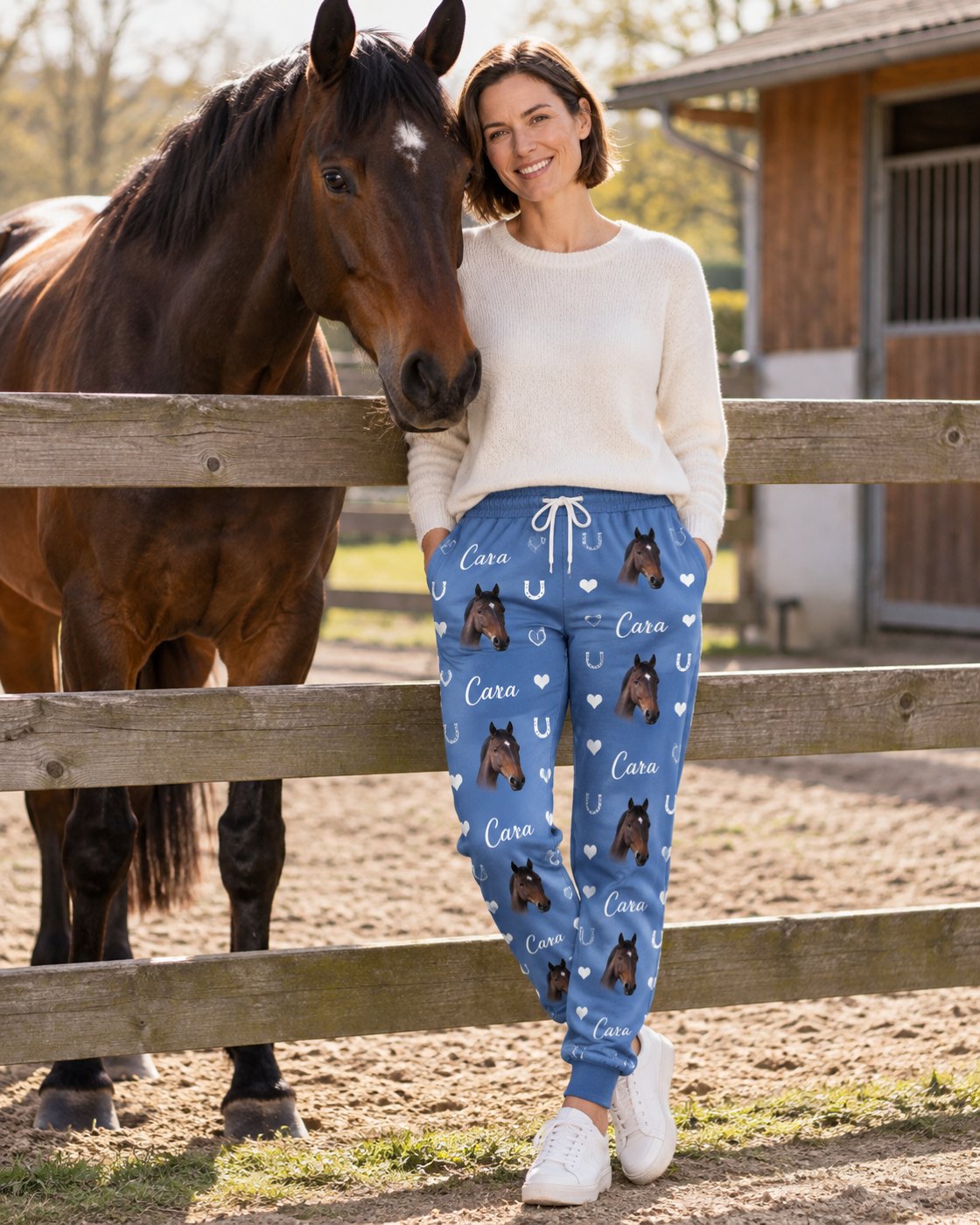 Personalisierte Jogginghose blau mit Pferdeköpfen und Name, am Koppelzaun, Pferd Cara